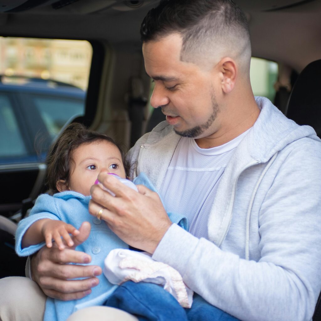 Primer plano de un padre dando el biberón a un bebé.